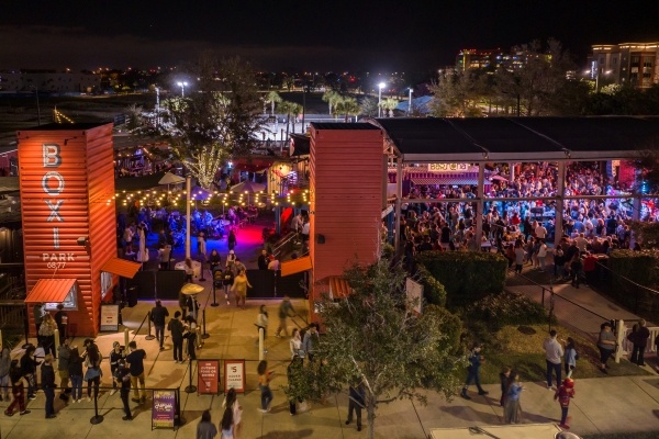 An aerial view of Boxi Park in Lake Nona at night with a large crowd of people enjoying entertainment onstage.  