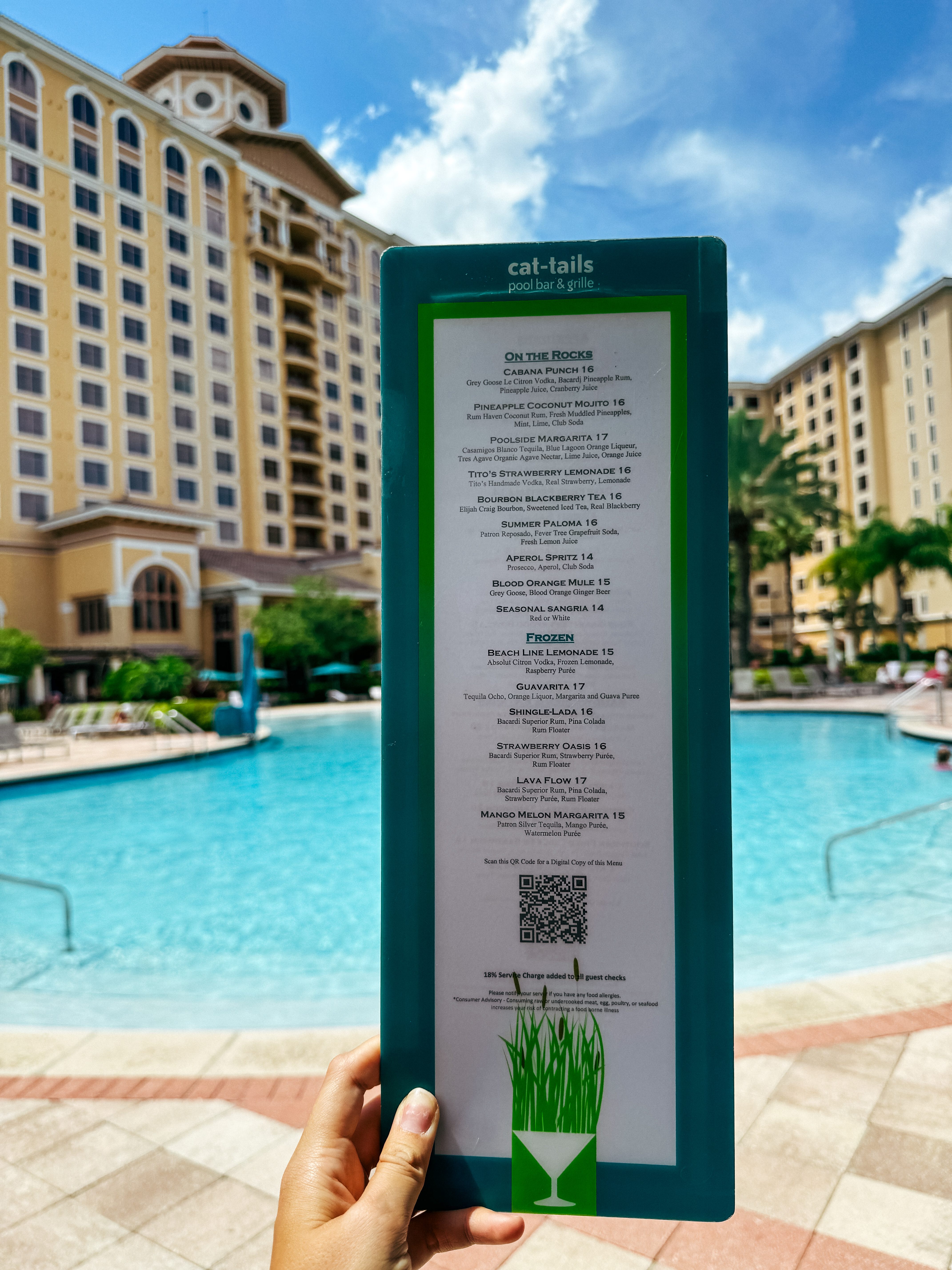 A close up image of a woman's hand holding up a menu for Cat-Tails Pool Bar & Grille in front of the pool at Rosen Shingle Creek. Try the Cat-Tails Four Grains Bowl for your healthy New Year's resolutions.