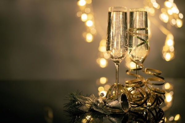 Two backlit glasses of Champagne surrounded by gold ribbon 