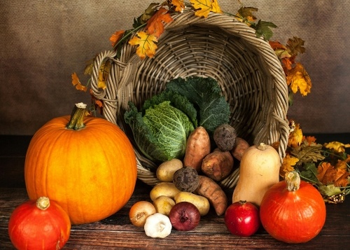 A rustic cornucopia with pumpkins, potatoes, pomegranates, and other fall produce. 